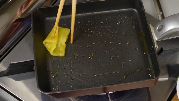 Chúng tôi sẽ làm tamagoyaki. Làm nóng chảo chuyên dụng cho tamagoyaki và dùng khăn giấy cho vào chảo một lớp dầu Ô-liu dày. Với đũa bếp, nhỏ vào chảo một ít hỗn hợp trứng và đảm bảo nó có tiếng xèo xèo.