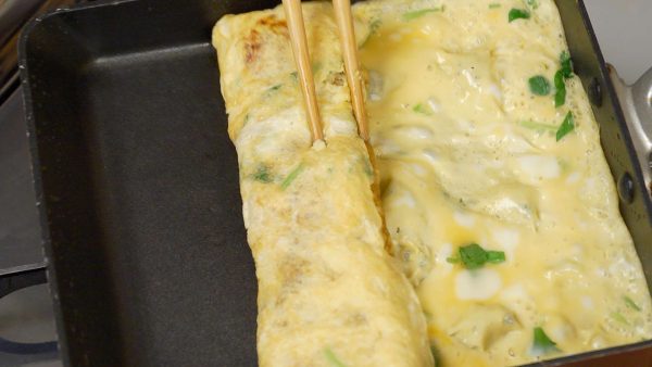 Khi trứng đã sắp cứng, thêm một lớp nữa cho tamagoyaki. Đẩy cuộn về phía trước và cho dầu vào chảo một lần nữa.