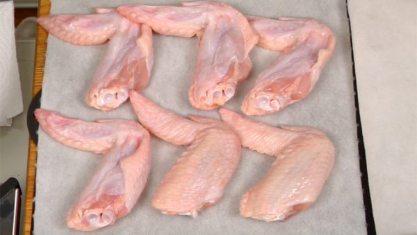 Let's prepare the chicken wings. Place the chicken wings onto a paper towel. Cover with another paper towel and press with your hands, removing all of the excess water.