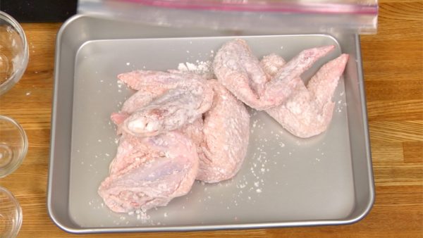 Press the chicken with a paper towel to lightly remove the excess liquid. Put the potato starch into a food storage bag. Place the chicken wings into the bag. Shake vigorously to coat the chicken with the starch. Place the chicken wings onto a cooking tray.