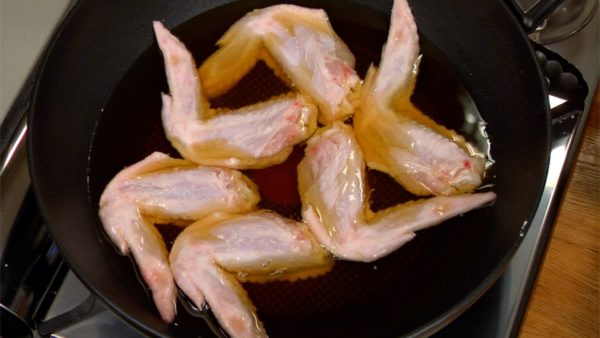 Retirez l'excès de fécule du poulet. Placez-les dans la casserole quand l'huile est encore froide. Faites frire le poulet sans mélanger jusqu'à ce que la surface soit cuite. Cela va aider à garder la fécule en place pendant la cuisson. 