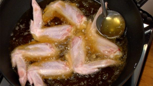Khi nhiệt độ bắt đầu tăng, múc dầu nóng lên gà để nấu triệt để. Dầu nóng thường bắn nên cẩn thận đừng làm bỏng chính mình.