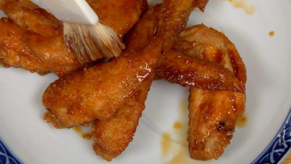 Servez les ailes de poulet Tebasaki sur une assiette. Avec un pinceau de cuisine, couvrez le poulet avec le reste de sauce.