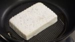 Add the sesame oil to a pan and turn on the burner. Place the tofu into the heated pan and saute the bottom.