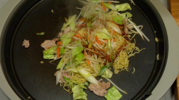 When the vegetables are almost cooked, mix the noodles with the vegetables. Pour on the Yakisoba sauce and stir-fry quickly.
