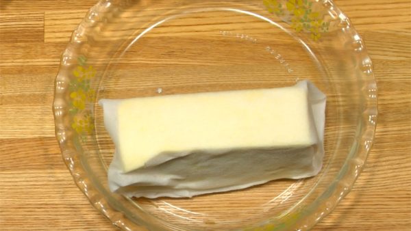 Préparez le tofu ferme. Coupez le tofu en deux. Enveloppez chaque bloc de tofu avec de l'essuie-tout et laissez reposer sur une assiette pour 30 minutes pour retirer l'excès d'eau. 