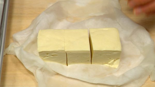 Après avoir retiré l'excès d'eau, retirez l'essuie-tout du tofu. Coupez chaque bloc en 3 morceaux. Épongez bien l'excès d'eau avec un essuie tout. 