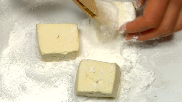 Placez le tofu dans un plat couvert généreusement de fécule de pomme de terre. Couvrez complètement le tofu avec la fécule. Retirez l'excès de fécule avec un pinceau.