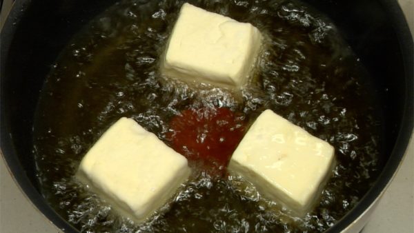 Plongez une pincée de fécule de pomme de terre dans l'huile chaude pour vérifier la température. La température devrait être aux environs de 170°C (340°C). Quand la fécule flotte avec un son grésillant, plongez doucement le tofu dans la friteuse. 