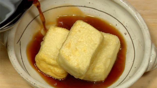 Préchauffez le bouillon et servez les 3 morceaux de tofu agedashi dans un plat. Trempez le tofu agedashi dans le bouillon chaud. 