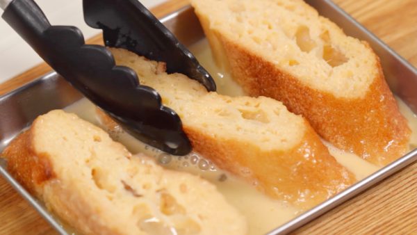 With tongs, squeeze each baguette and then flip it over. The squeezing will help it absorb the custard mixture quickly. Then, let the bread sit for about 5 more minutes.