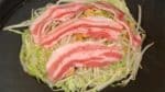 Rada upp fläsksidoskivorna på toppen och tillaga i cirka 5 minuter. Se till att okonomiyakin inte fastnat på järnet.