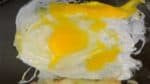 Limpiar la plancha con un paño de cocina humedecido y luego volver a colocarle aceite. Añadir el huevo, romper la yema y darle forma de círculo.
