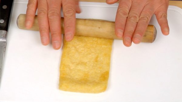 Let’s prepare the aburaage, fried tofu pouches. Roll out each fried tofu with a rolling pin. This will make the fried tofu easy to open.