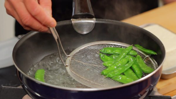 Remove the firm stringy fibers of the snow peas. You can also use snap peas or string bean pods instead. Add salt to a pot of boiling water to help keep the peas from getting soggy. Boil the snow peas for about 1 minute. Remove and strain the peas with a mesh strainer.