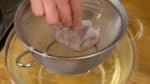 Ensuite, filtrez le bouillon dashi avec une passoire couverte d'un essuie-tout. Essorez légèrement les copeaux de bonite et maintenant le bouillon dashi clair pour les udon est prêt !