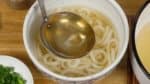 Pour a generous amount of the hot udon broth over the noodles.