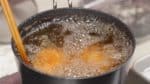 Ne les touchez pas jusqu'à ce que la pâte se solidifie sinon la couche extérieure va se casser. Ensuite, avec des baguettes de cuisine, faites tourner doucement les œufs pour les dorer uniformément. Faites frire pour environ 5 minutes et demi jusqu'à ce qu'ils soient bien dorés. 