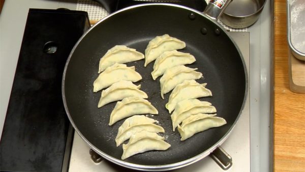Let's cook the gyoza. Heat the sesame oil in a frying pan over medium heat. Arrange the half of the gyoza in the pan. Make a little space between each Gyoza so that they don't stick together.