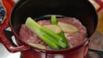 Place the chicken into a heavy pot. Place the green part of the long green onion and ginger root slices onto it. Add the sake and the water. Heat the pot on medium heat. Cover but leave the lid slightly off so that you can see inside.