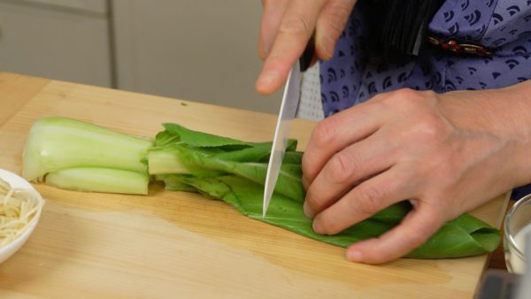 Add the sesame oil to a pot of boiling water. Cut the bottom of the bok choy, detaching the outer leaves. Then, cut the leaves into 3 pieces.