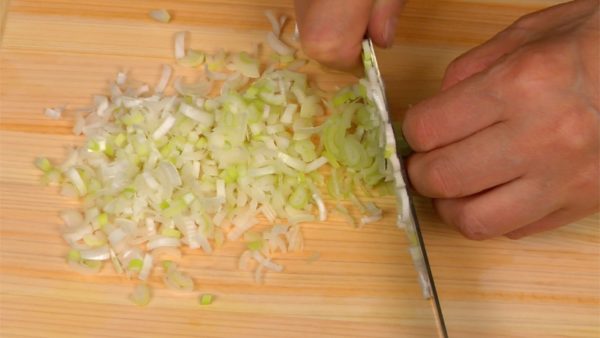Make a cut in the long green onion lengthwise. Turning it halfway over, make another cut across the first, quartering the onion lengthwise. Chop the long green onion into fine pieces.