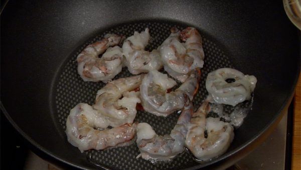 Let’s stir-fry the prawns. Put the vegetable oil in the heated pan. Swirl the pan to coat it with the oil. Spread the prawns in the pan and adjust the heat to medium.