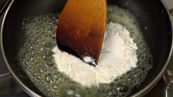 Let’s make the roux. Drop the butter in the pan over low heat. Let the butter melt in the pan. Add the sieved flour to the melted butter. Stir-fry the flour thoroughly with a wooden paddle. Be careful not to burn the mixture.