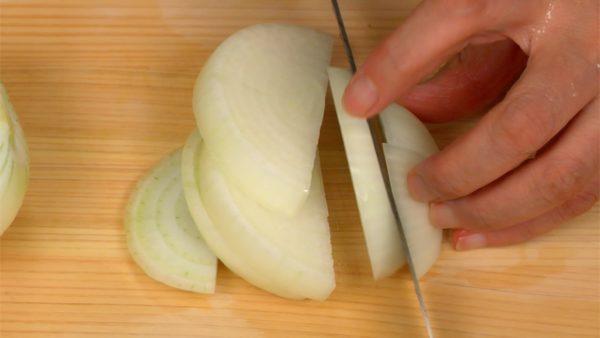 Let’s cut the vegetables. Cut the onion in half. Remove the basal plate, the part of the root attached to the onion. Make a shallow cut vertically along the outer layers. This will help cut the onion into even pieces. Slice the onion across the shallow cut, making half inch slices.
