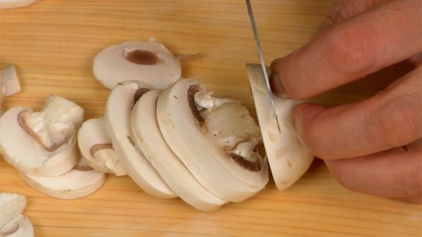 Cut the carrot vertically into 4 slices. Stack the slices on top of each other and chop them into fine strips. Slice the button mushrooms into thin slices.