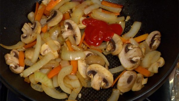 When the aroma grows stronger, add the sliced button mushrooms and mix. When the mushrooms begins to wilt, add the tomato ketchup and toss to coat.