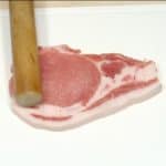 고기 파운더로 돼지 고기 슬라이스를 부드럽게 만드세요. 한쪽에 소금과 후추를 뿌린다.