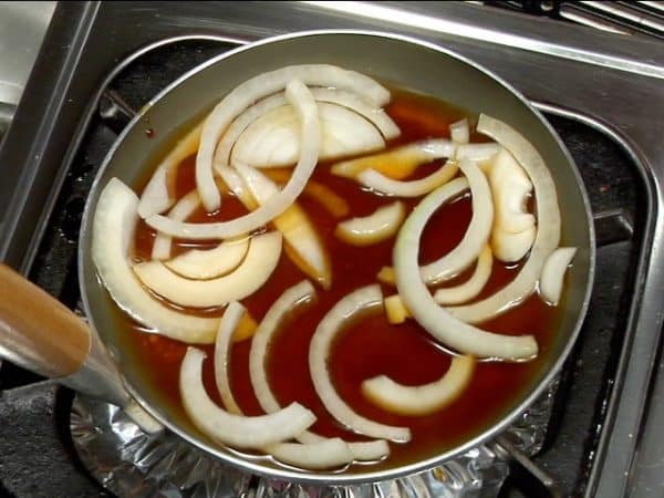 Приготовим соус кацудон. Смешайте воду, порошок бульона даси, соевый соус, мирин, сахар и лук в небольшой горшок. Слегка перемешайте палочками для еды.