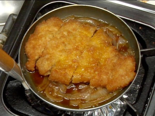 When the onion is completely cooked, place the tonkatsu into the pan.