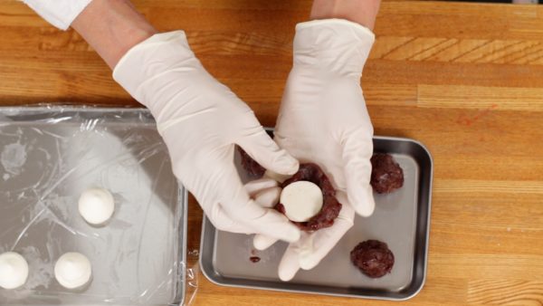 Now, the cream is completely frozen. Quickly flatten the anko, red bean paste. Cover the frozen cream with the anko. The food preparation gloves will help to avoid softening the cream.