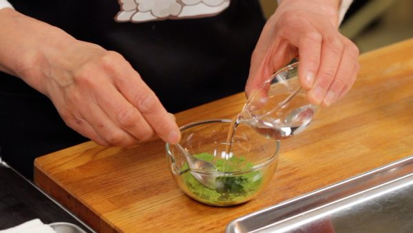 Diluez la poudre de thé vert matcha avec de l'eau. Ajoutez une quantité minimale d'eau pour la dissoudre. Saupoudrez une quantité généreuse de fécule de pomme de terre sur un plateau. Nous allons diviser du mochi très collant sur ce plateau plus tard. 
