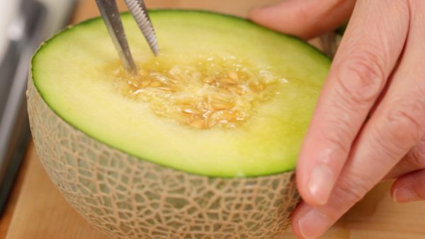 Coupez le melon Galia ou Cantaloup en deux dans la hauteur. Avec des ciseaux de cuisine, détachez les graines et les fibres du centre. Ensuite, mettez les graines et les fibres dans une passoire. 