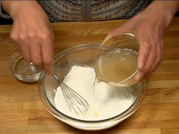 Chúng tôi sẽ làm bột cho bánh xèo Okonomiyaki. Trộn bột bánh bông lan và bột nở trong bát và đảo cùng nhau bằng phới (whisk). Hòa tan bột nước dùng dashi cá ngừ bonito trong nước và thêm dần dần nước dùng dashi trong khi trộn. Điều này giúp tránh có cục bột nào,