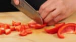 Coupez le poivron rouge en deux dans la longueur et retirez la tige et les graines. Coupez le poivron en tranches de 1.5 cm (0.6 inch). Ensuite, coupez-les en morceaux plus petits. 