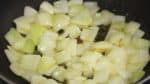 Quand la gousse d'ail est un peu dorée et que ça sent bon, ajoutez l'oignon en morceaux. De temps en temps, secouez la poêle et faites cuire doucement l'oignon. 
