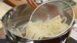 Cocinemos los fideos. Echa los fideos congelados en una olla con agua hierviendo. Despega los fideos. Y retira los fideos con un colador de malla.