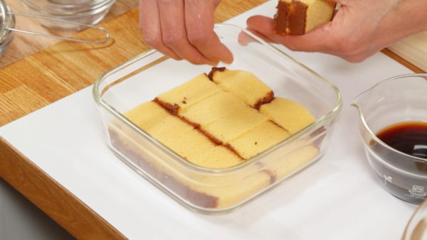 Slice the castella sponge cake into 1.5cm (0.6") slices. Line up the castella pieces on the bottom of the container.