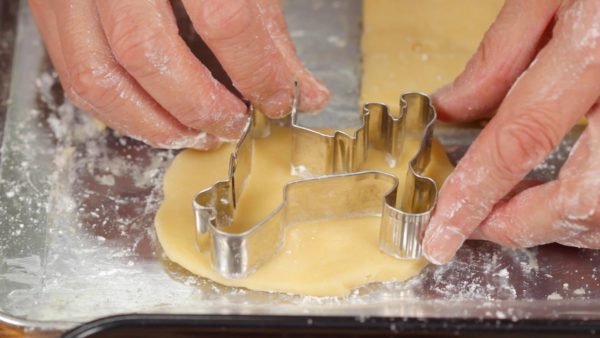 Coat your hands with flour. Gather the leftover dough and shape it into a flat circle. Coat a poodle-shaped cutter with flour and then cut out the dough. If the dough is too soft to shape, chill it in the fridge or freezer to harden.