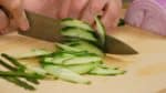 去皮器用条纹方式把黄瓜去皮。纵向切成两半。然后把它用对角线切的方式切成薄片。