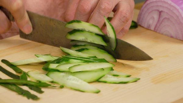 Peel the cucumber with a peeler in a striped pattern. Cut it in half lengthwise. Then, slice it into thin slices using diagonal cuts.