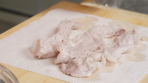 Stir the slices until they turn white and place them onto the cutting board covered with a paper towel. Remove the excess water thoroughly. Then, cut the pork into bite-size pieces.