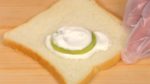 Let’s make the fruit sandwiches. Spoon the yogurt cream onto the sliced bread. Place the sliced kiwi fruit onto the cream layer and then cover it with the cream.