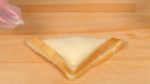 Use your weight to press the cutter, separating the bread crusts. Remove the cutter and now the triangular sandwich is ready.