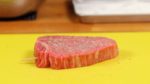 Lasst uns Gyukatsu machen. Das hier ist ein 3cm dickes marmoriertes Wagyu Steak, aber ihr könnt auch Rindfleisch oder ein Lendenstück nehmen. Nehmt das Rindsteak vorher aus dem Kühlschrank raus und lasst es 30 Minuten auf Zimmertemperatur bringen. Streut das Steak auf beiden Seiten mit Salz und Pfeffer.