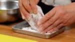 Phủ một lớp bột mỏng lên thịt trên khay. Ở Nhật, bột bánh ngọt thường được sử dụng nhưng bạn cũng có thể thay thế bằng một mì đa dụng.